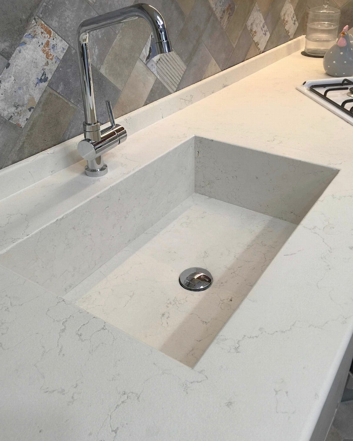 12 Latest Kitchen Sink Design Ideas for 2026 6 White marble-patterned integrated kitchen sink set into a matching countertop with a chrome faucet.