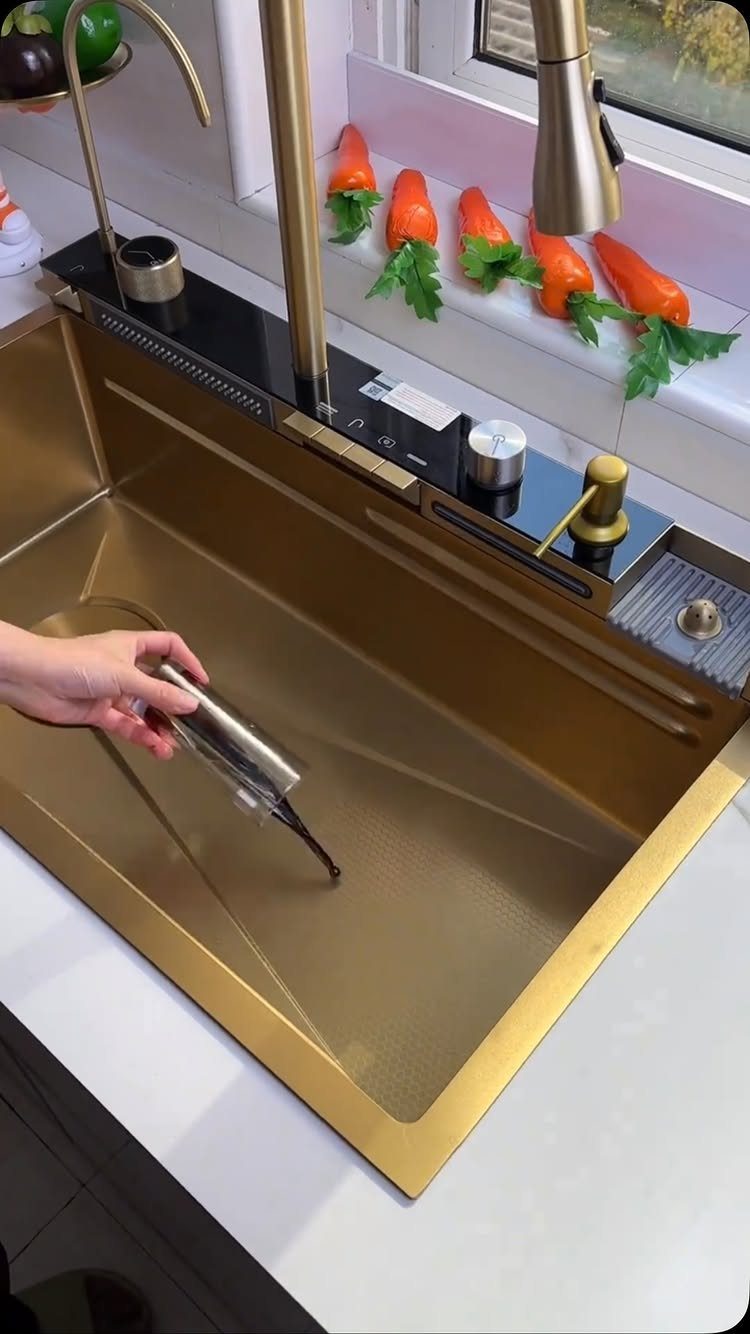 12 Latest Kitchen Sink Design Ideas for 2026 11 A hand uses a tool inside a modern gold workstation kitchen sink.