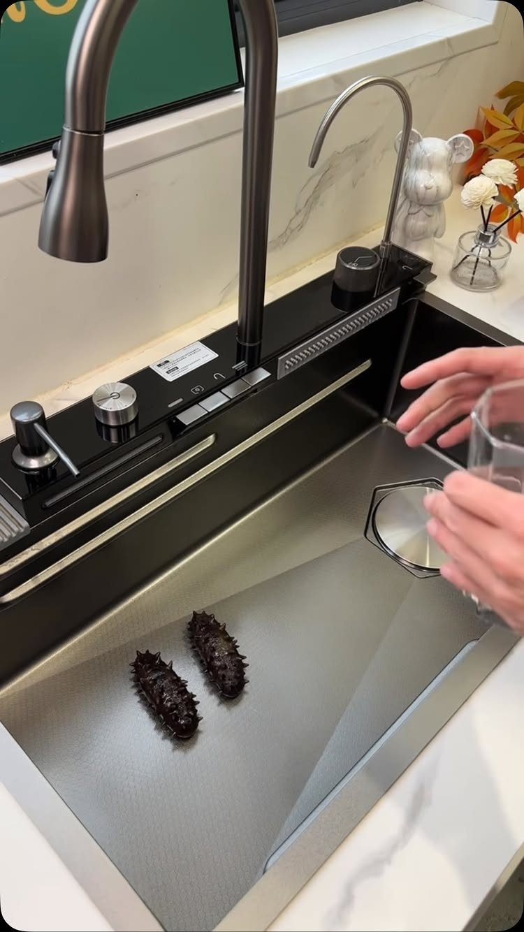 12 Latest Kitchen Sink Design Ideas for 2026 8 A person pouring water into a modern stainless steel workstation kitchen sink.
