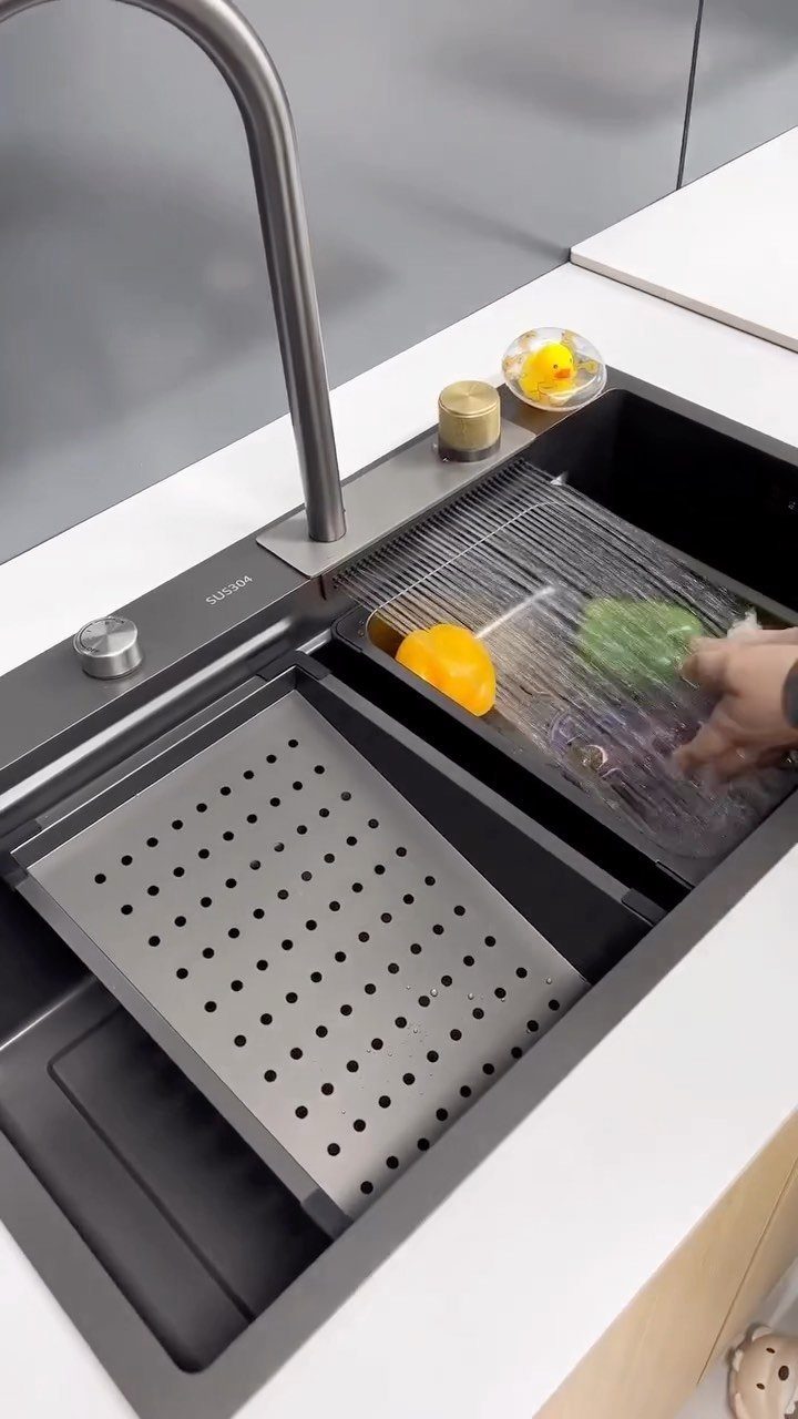 12 Latest Kitchen Sink Design Ideas for 2026 9 A dark grey workstation sink with integrated colander and drying rack in a white kitchen countertop.