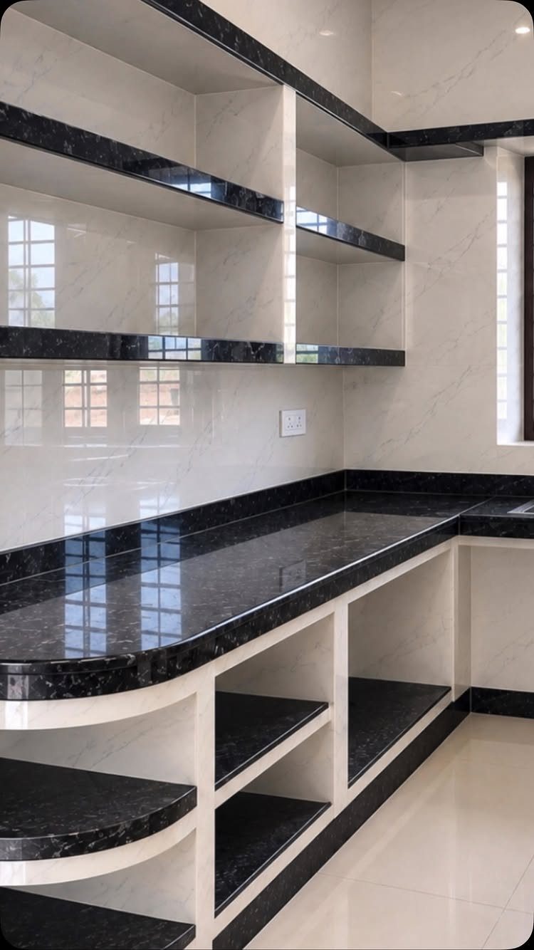 Black granite countertops with white speckles installed in a modern white kitchen with open shelving.