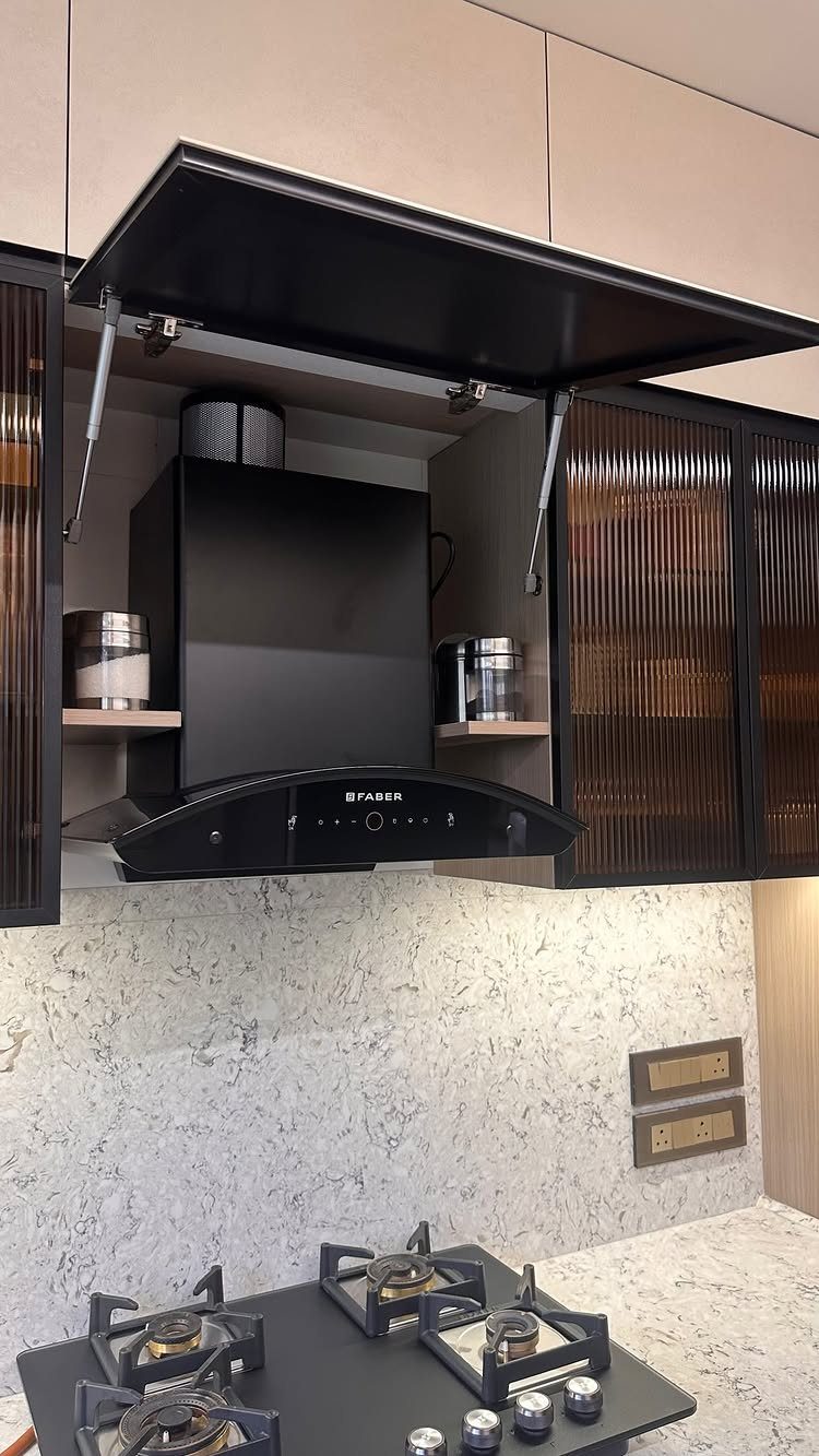 A black kitchen range hood installed above a gas stovetop with speckled countertops.