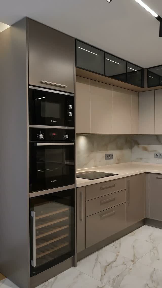 Modern kitchen cabinetry with integrated black oven, microwave, and wine cooler against a marble backsplash.