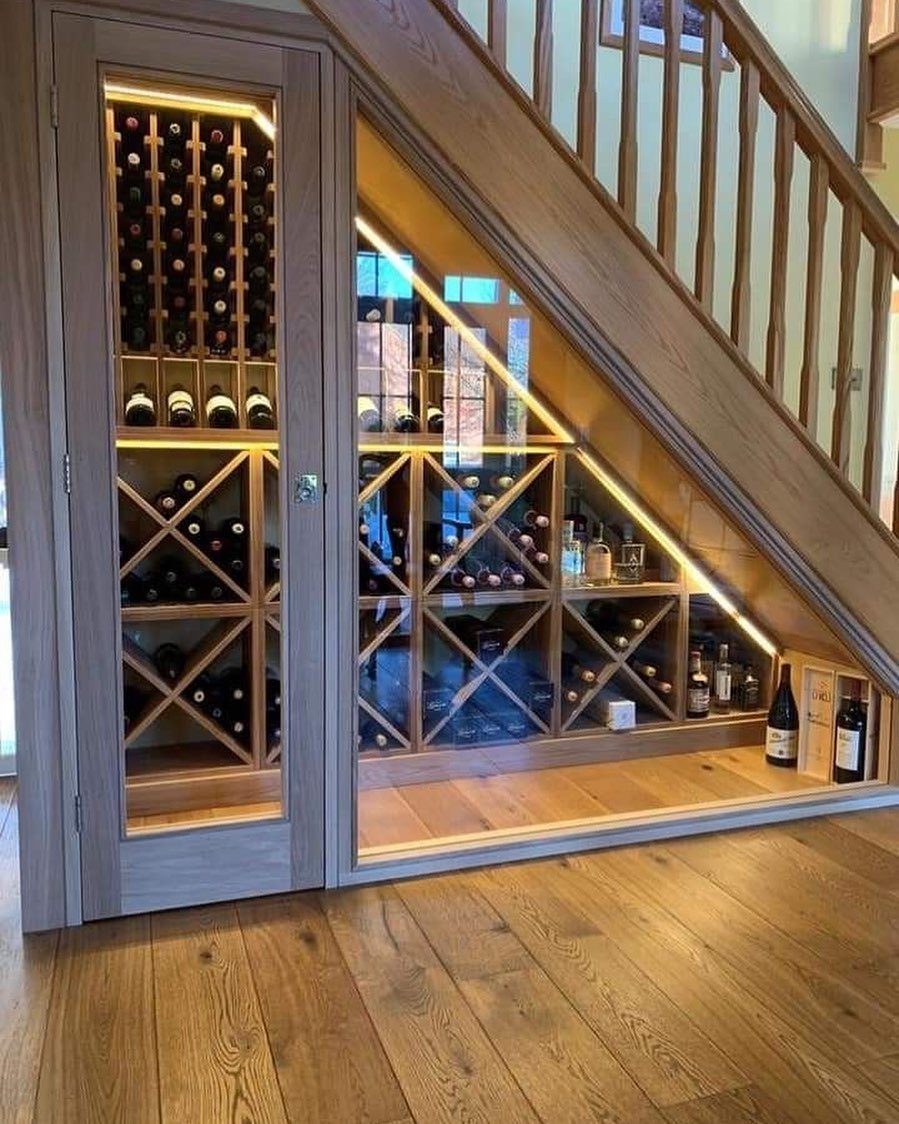 Wooden wine rack with integrated lighting built into the space under a staircase.