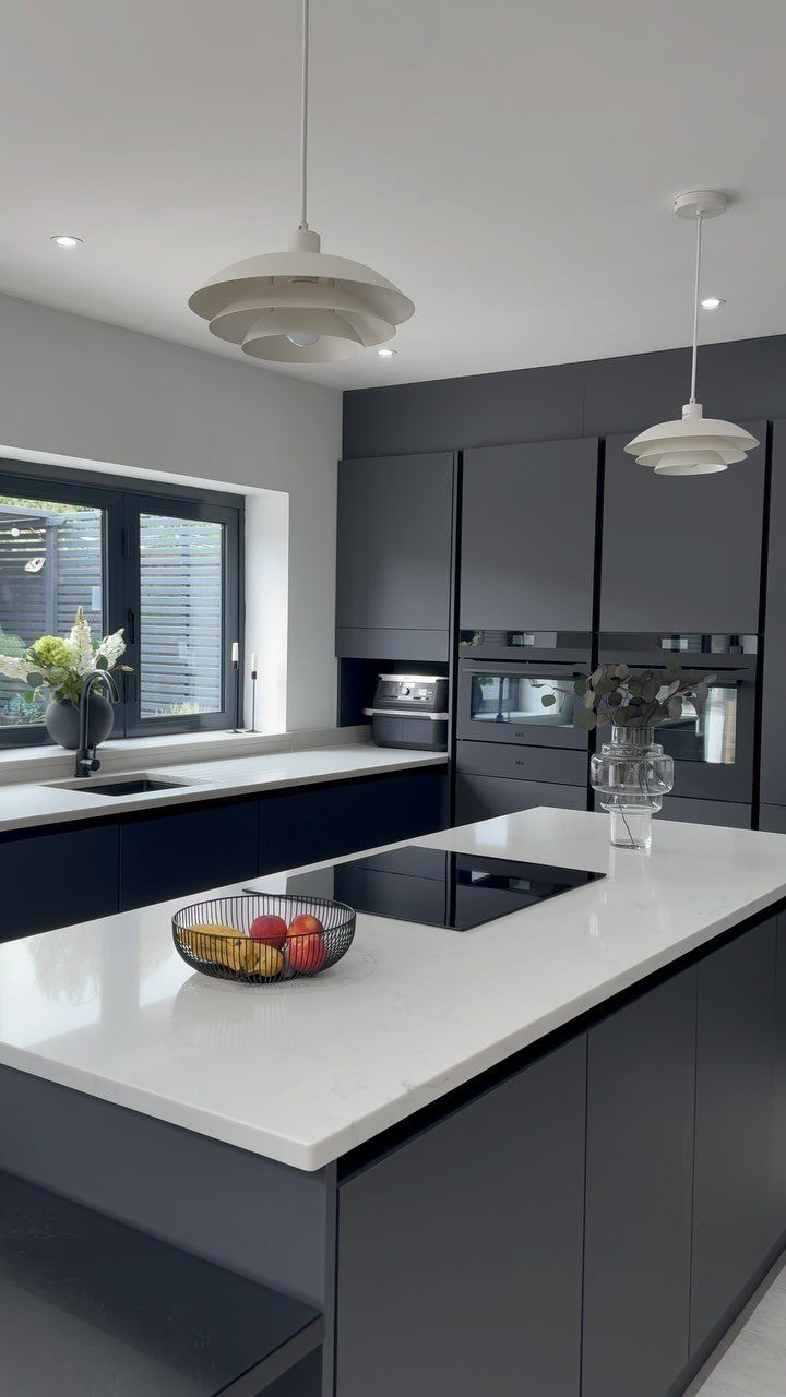 Modern kitchen with dark grey flat-panel cabinets and a white quartz island countertop.