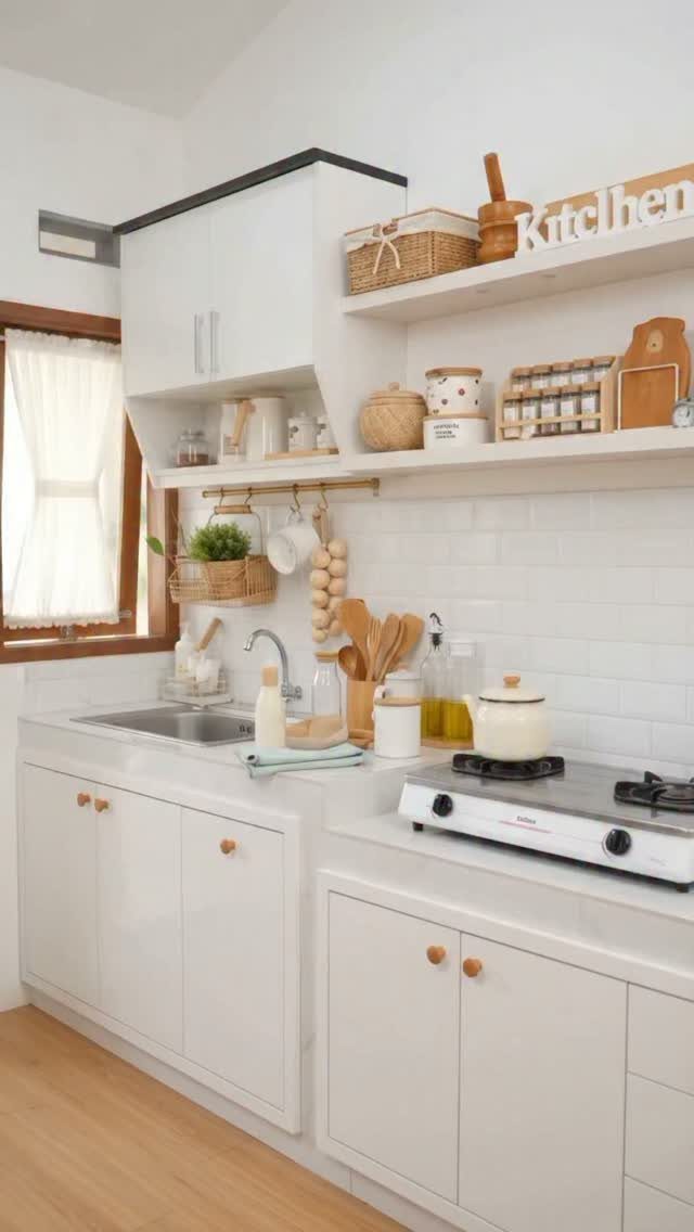 White kitchen cabinets with wooden knobs and open shelves holding various kitchen accessories.