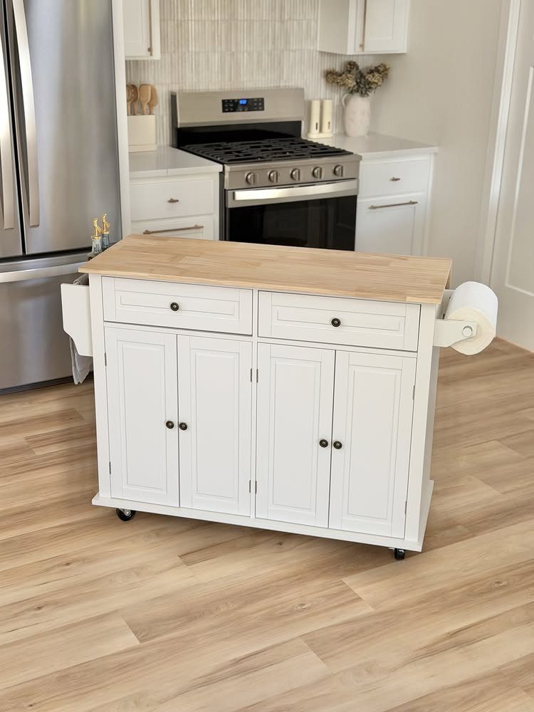 A white mobile kitchen island with a wooden countertop and storage cabinets on a light wood floor.