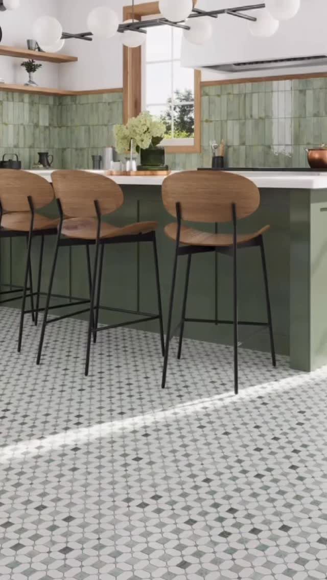 Green textured tile backsplash behind a kitchen island with wooden bar stools and patterned floor tiles.
