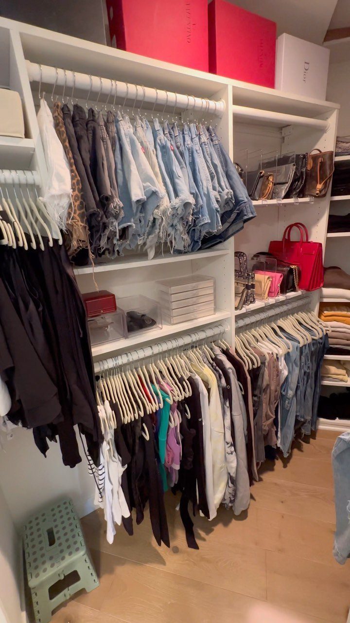 11 Ideas to Organize a Closet for Maximum Storage 1 Organized white closet shelves featuring uniform hangers holding various clothing items and colorful handbags.