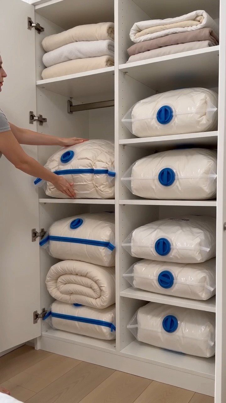 11 Ideas to Organize a Closet for Maximum Storage 11 A person placing a white vacuum-sealed bag onto a white closet shelf filled with bedding.