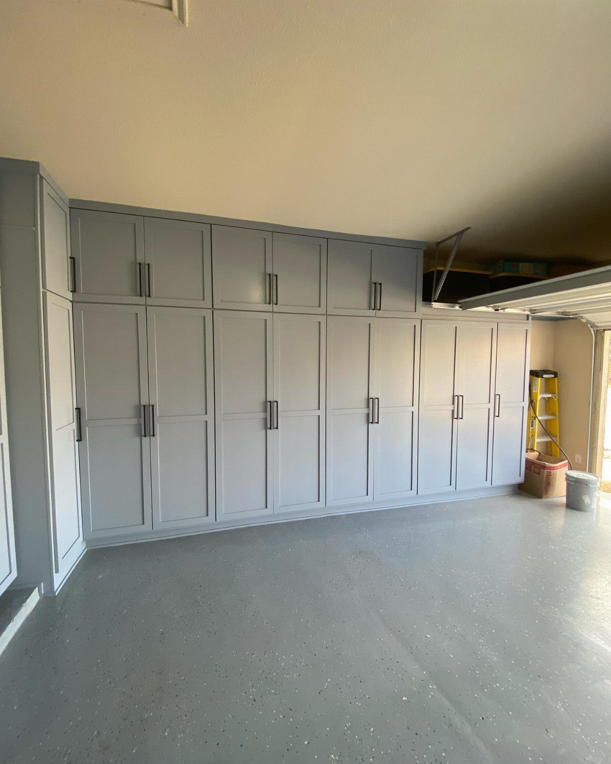 22 Organize a Garage Ideas for Workbenches, Zones & Wall Systems 13 Large light gray built-in garage cabinets with dark handles installed against a wall.