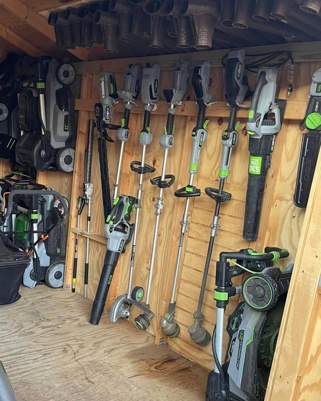 22 Organize a Garage Ideas for Workbenches, Zones & Wall Systems 6 Cordless yard tools hanging organized on a wooden wall in a storage shed.