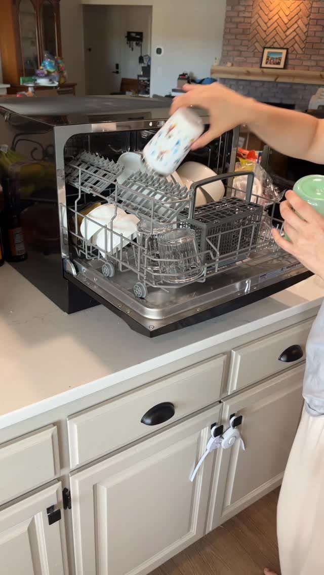 20 Simple and Small Kitchen Design Ideas 9 A person loading white dishes into a small countertop dishwasher on a white kitchen counter.