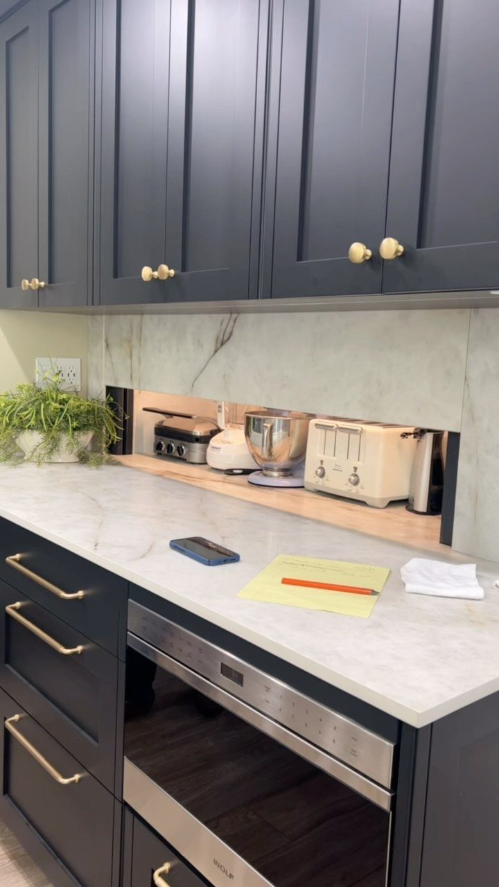 20 Simple and Small Kitchen Design Ideas 13 Dark blue kitchen cabinets with gold handles and a marble countertop featuring a recessed appliance shelf.