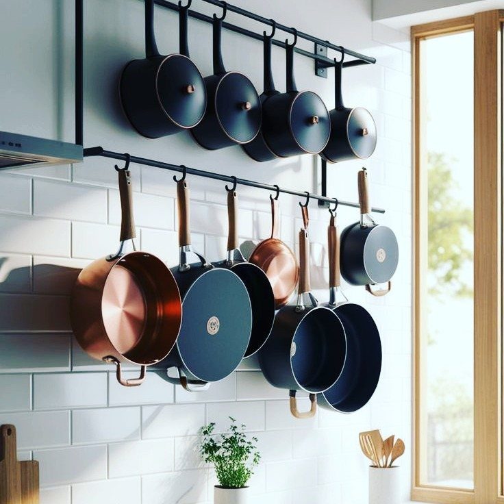 20 Simple and Small Kitchen Design Ideas 8 Black and copper pots hanging from metal pot racks against a white subway tile wall.