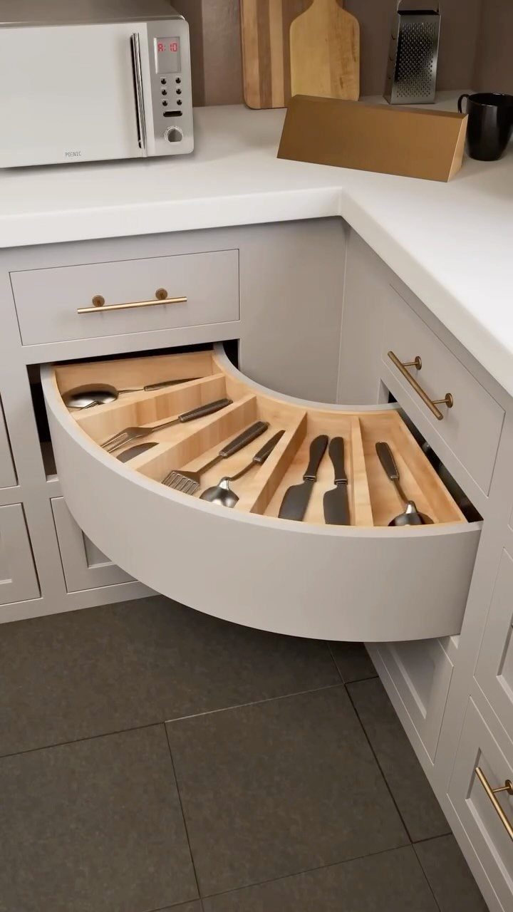 20 Sleek Kitchen Cabinet Design Ideas for 2026 20 A curved light grey kitchen drawer pulled open to reveal organized silver cutlery inside.