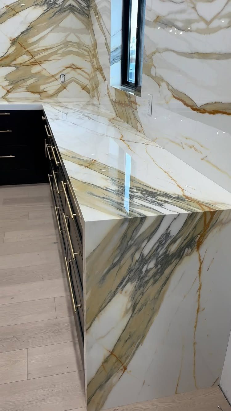 20 Sleek Kitchen Cabinet Design Ideas for 2026 14 Polished marble countertop with gold and grey veining featuring a waterfall edge design.
