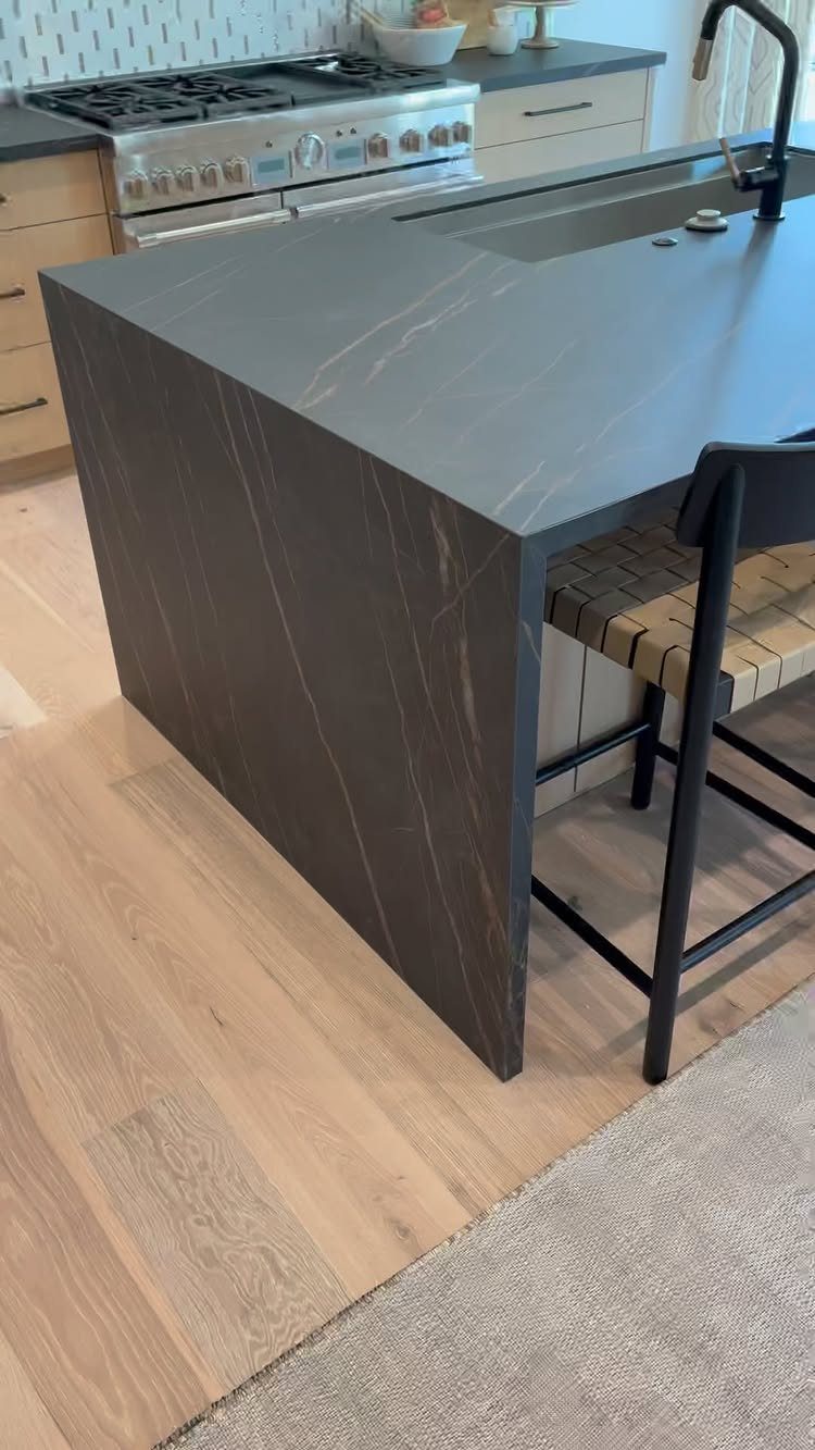 20 Sleek Kitchen Cabinet Design Ideas for 2026 15 Dark grey marble-patterned kitchen island featuring a seamless waterfall countertop edge and black faucet.