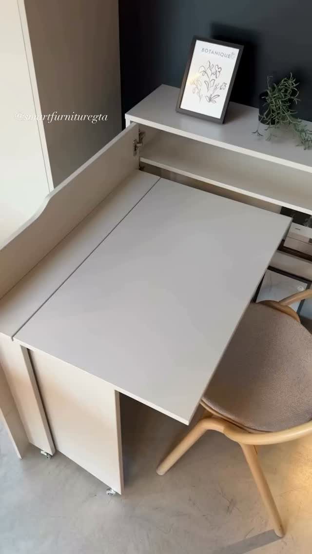 A white fold-out desk extended from a cabinet with a light wood chair nearby.