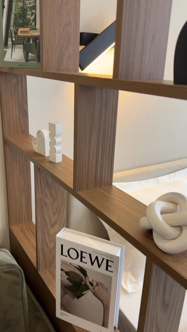 14 Small Apartment Storage Hacks and Genius Finds for 2026 5 Wooden open-shelf room divider holding decorative objects and books in a modern apartment.