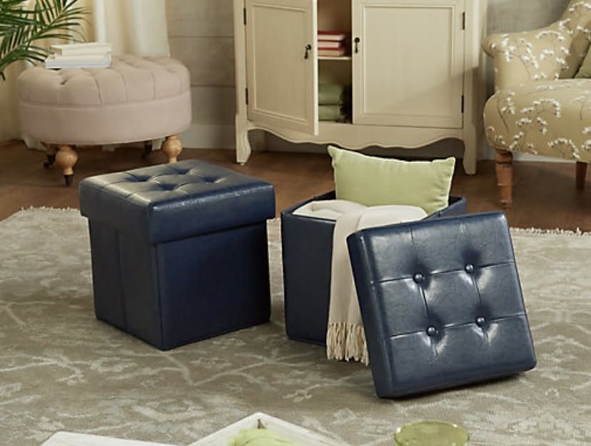14 Small Apartment Storage Hacks and Genius Finds for 2026 2 Two navy blue tufted leather storage ottomans on a patterned rug in a living room.