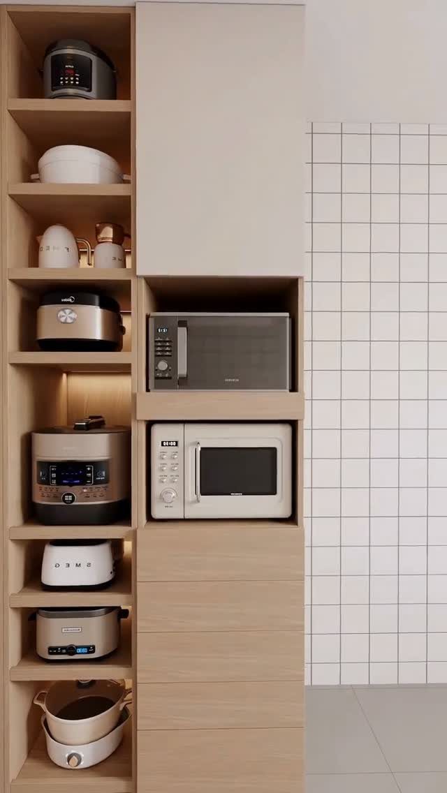 Light wood pantry cabinets containing various kitchen appliances and stacked microwaves in a built-in niche.