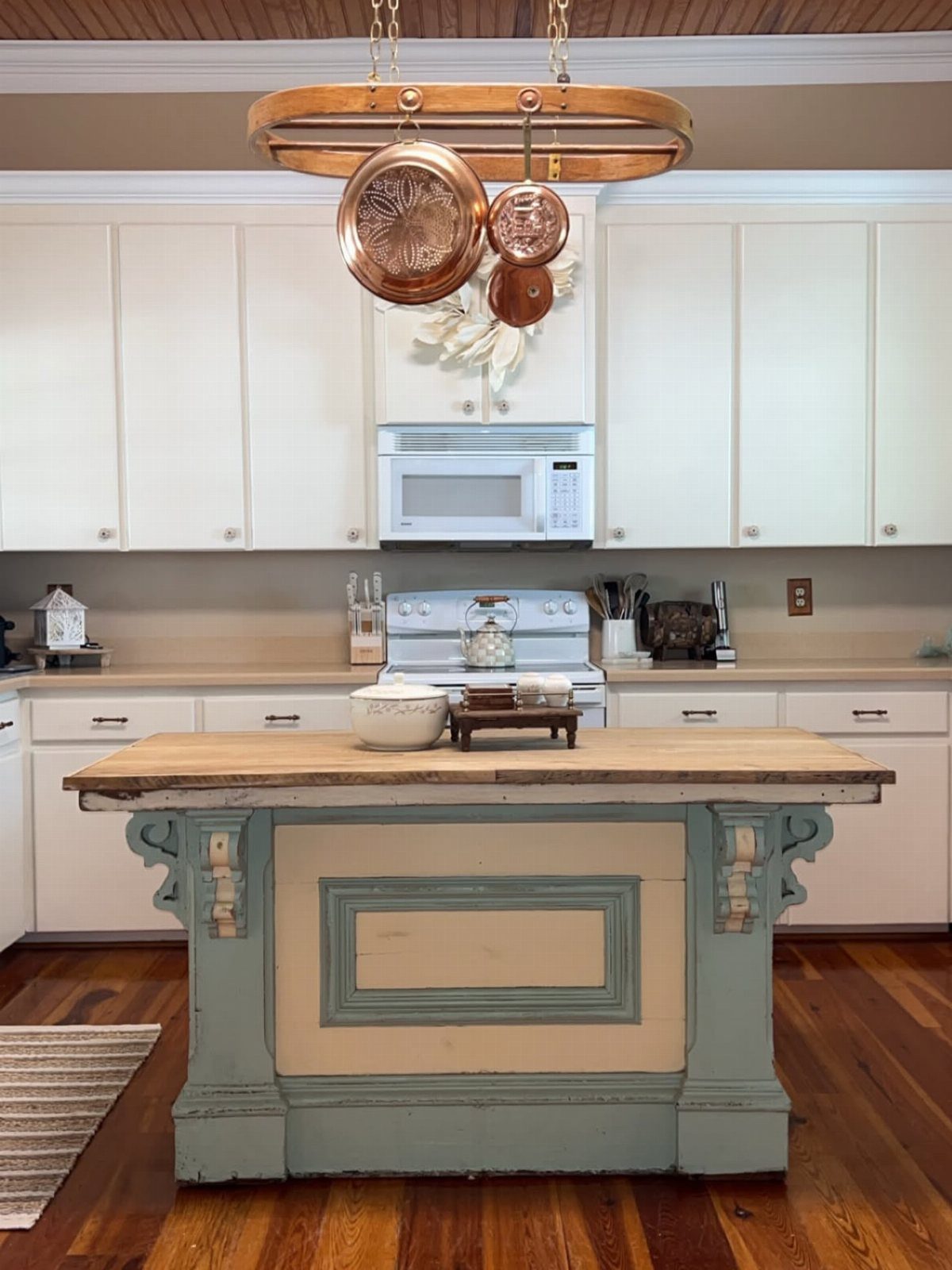 A rustic kitchen island with a wooden top and decorative corbels on a blue base.