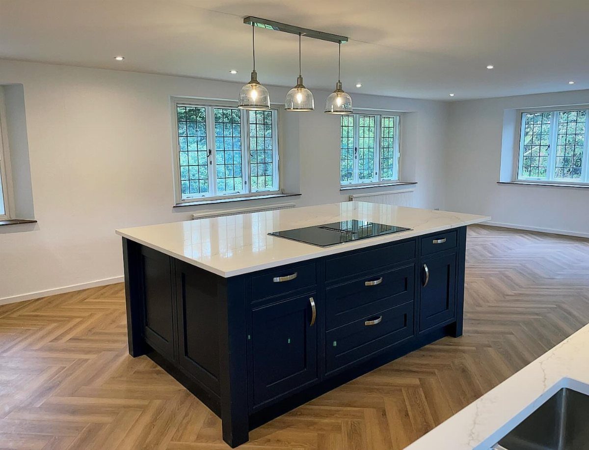 A navy blue kitchen island with a white marble top and built-in induction hob.
