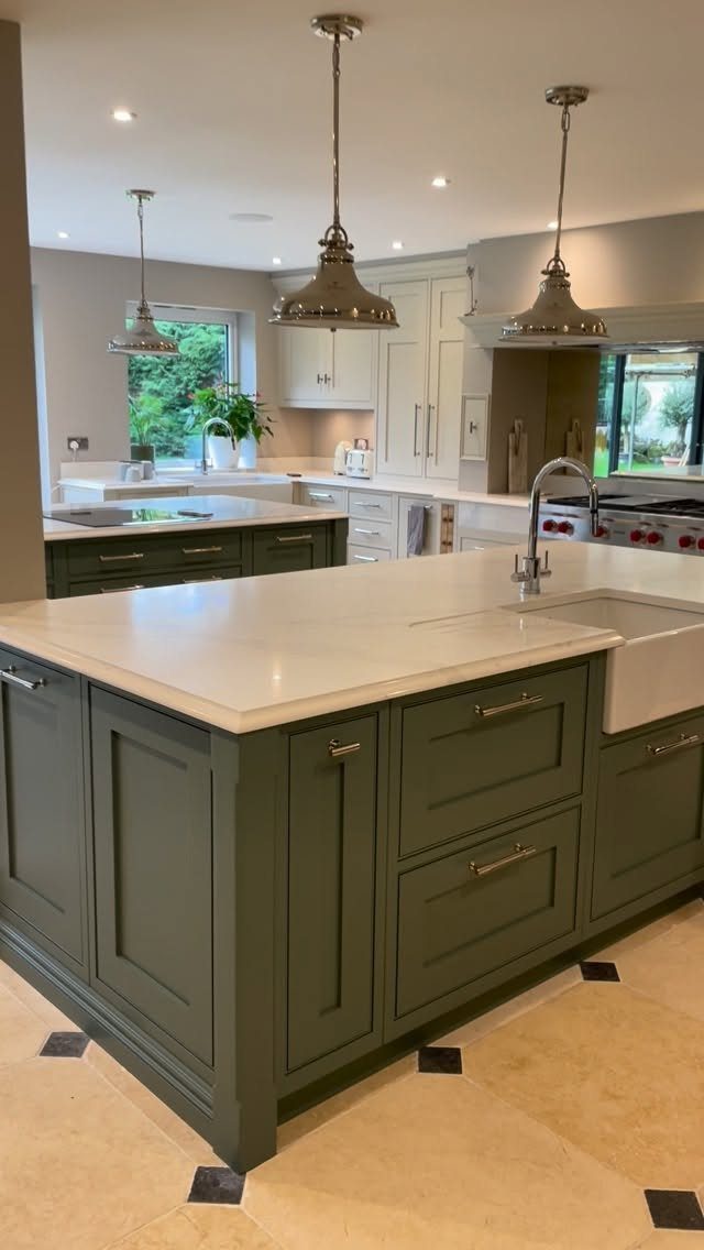 A sage green kitchen island with a white stone countertop and integrated farmhouse sink.