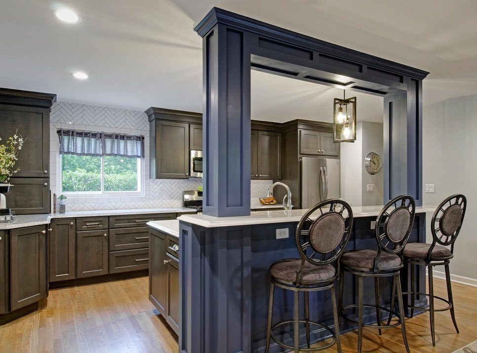 A navy blue two-tier kitchen island with bar stools and a white countertop.