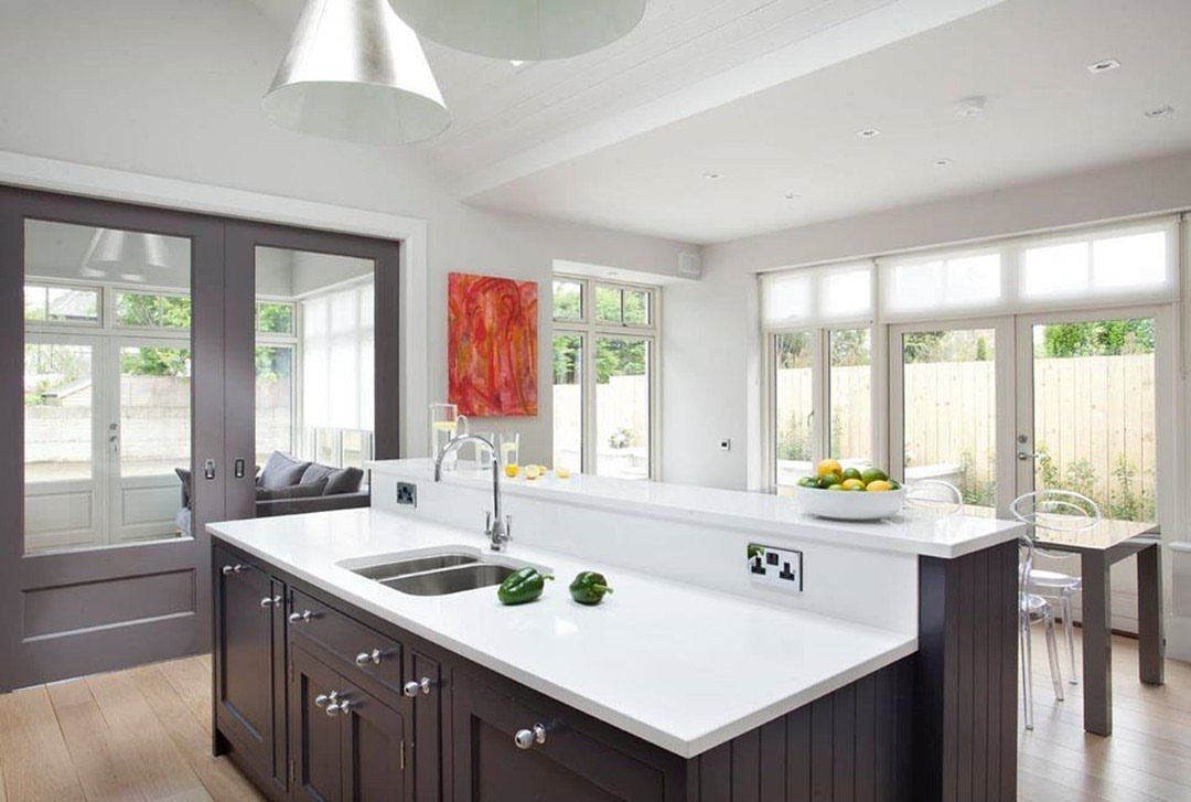 A modern kitchen island featuring two different white countertop heights and dark wood cabinets.