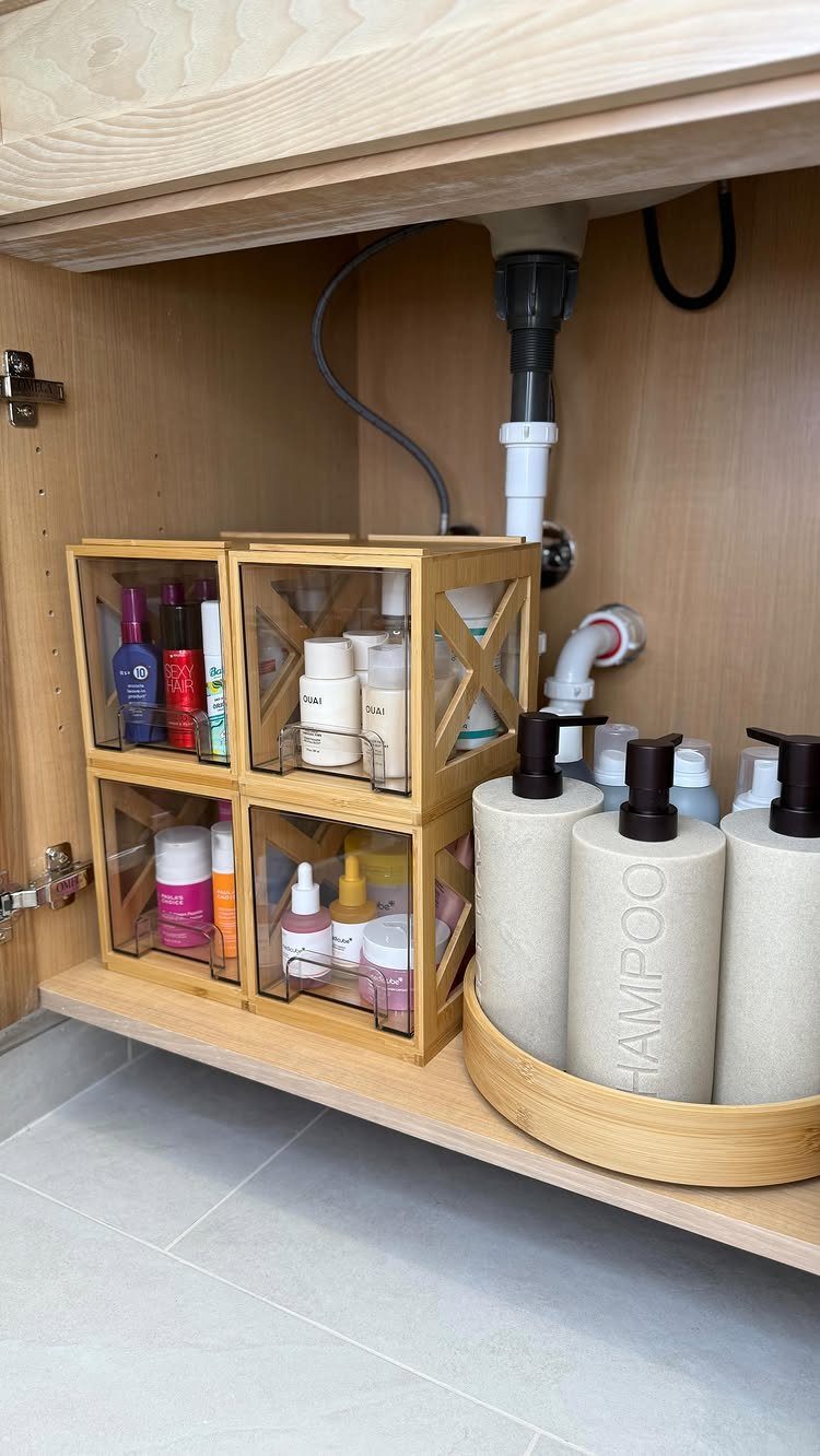 Large beige shampoo bottles sitting on a wooden rotating turntable inside a bathroom cabinet.