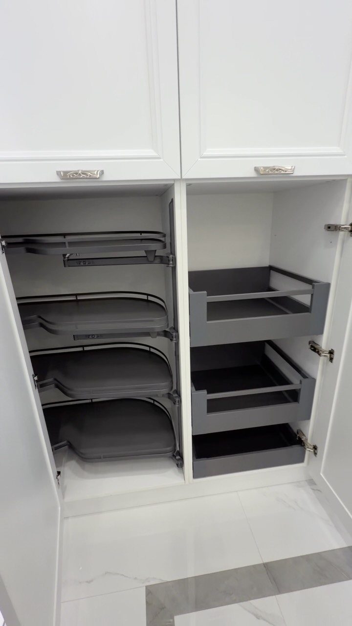 Vertical Pull Out Cabinet Kitchen: 7 Ideas That Fix Stiff Necks 3 Open white kitchen cabinets showing grey pull-out shelves and deep tray-style storage drawers.