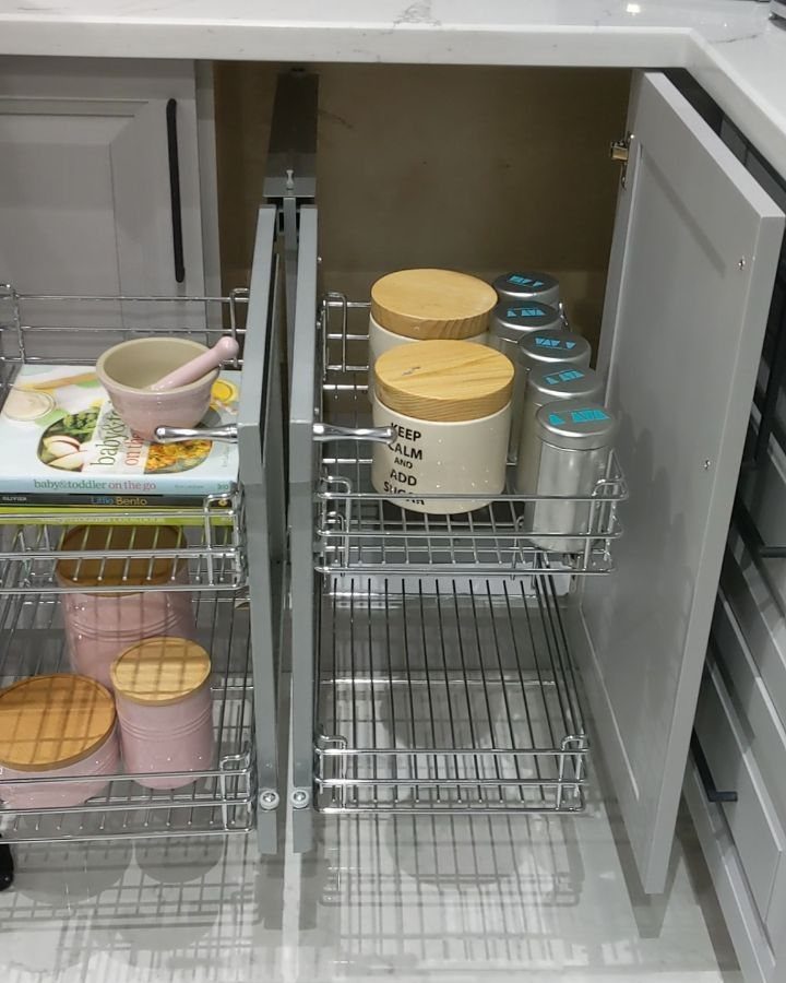 Vertical Pull Out Cabinet Kitchen: 7 Ideas That Fix Stiff Necks 6 Silver wire pull-out baskets containing canisters and cookbooks inside a grey kitchen cabinet.
